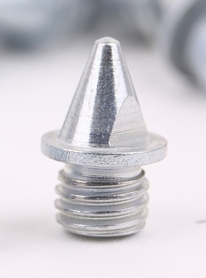 Gros plan sur un crampon à glace en métal avec filetage pour la fixation aux chaussures. Idéal pour une bonne adhérence sur la glace.