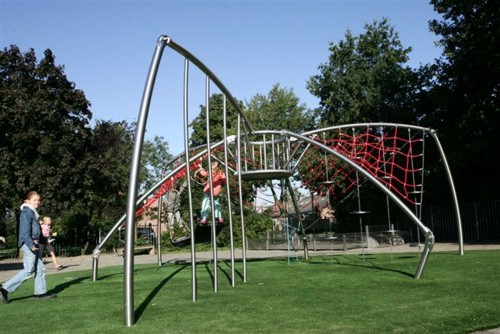 Des enfants jouent sur une structure d'escalade moderne en métal et en cordes sur une aire de jeux verte en plein air