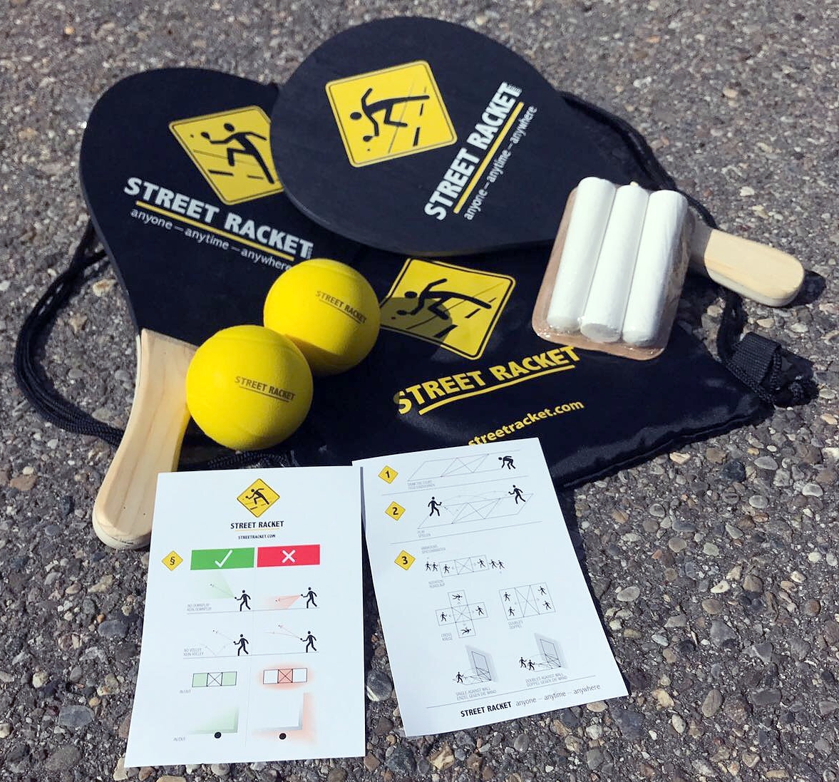 Street Racket Set mit Schlägern, gelben Bällen, Anleitung und Kreide auf Asphalt
