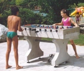 Kinder spielen Tischfußball auf einer Terrasse im Freien